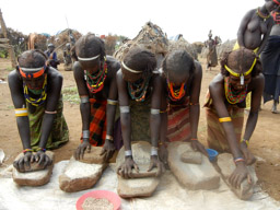Dassanach women grinding grain               Omorate, Ethiopia